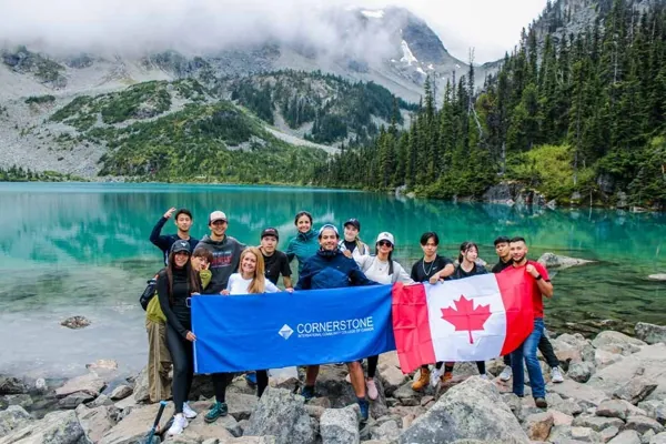 Students sharing a mountain lake day trip with Canadian and Cornerstone flags