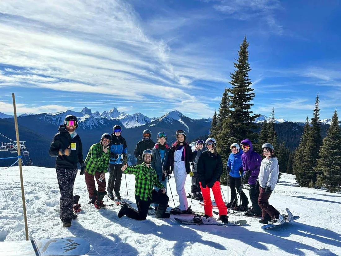 Students skiing and snowboarding together on a snowy mountain